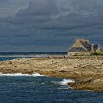 Eines der restaurationsbedürftigen Häuser auf den Rochers. Im Hintergrund ist der Plage de Pors Carn zu sehen