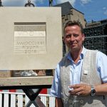 Steinmetzmeister Markus Heindl neben seinem Werk. Im Glas befindet sich kühles Wasser!